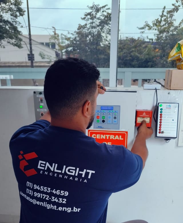 Técnico da Enlight Engenharia realizando teste na central de alarme de incêndio com acionador manual