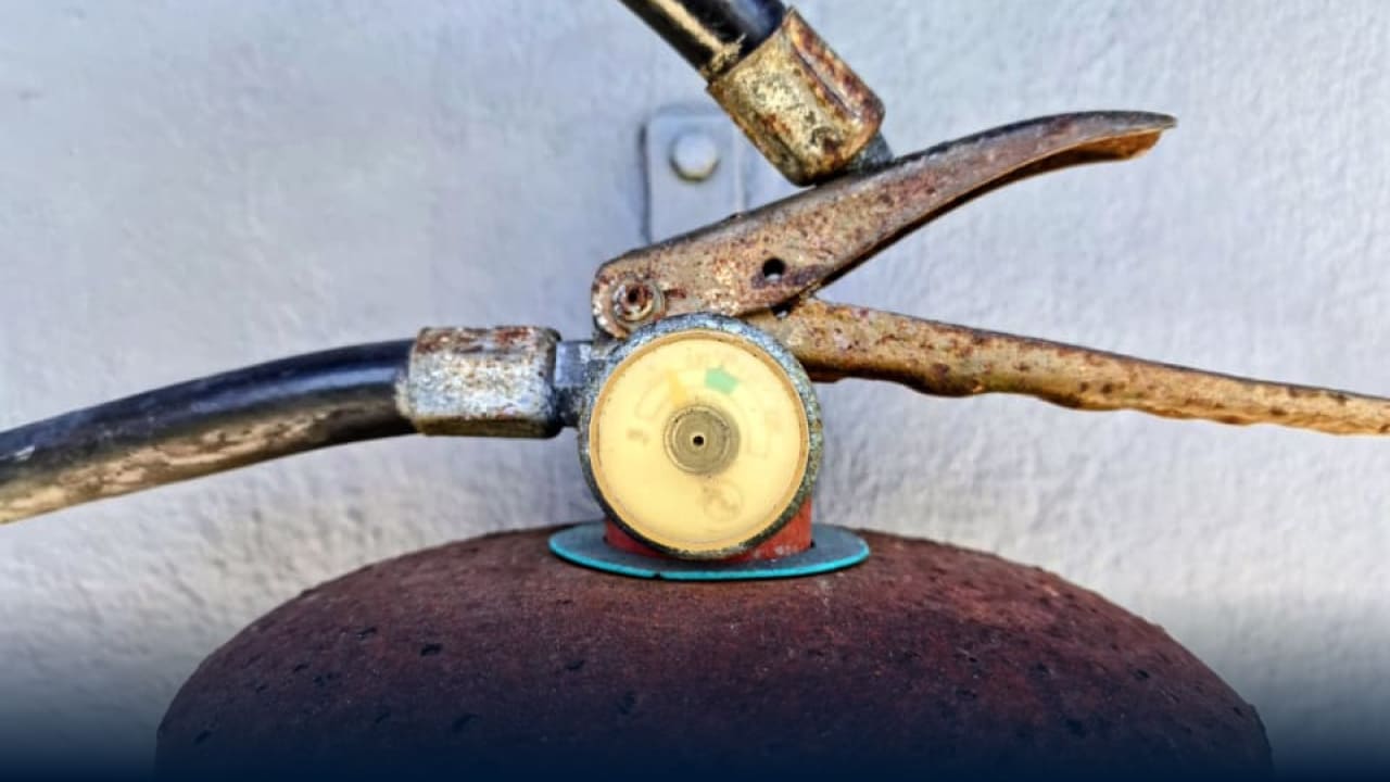 Detalhe de extintor de incêndio antigo e enferrujado com manômetro, evidenciando a necessidade de verificar a Renovação AVCB CLCB e manutenção preventiva.