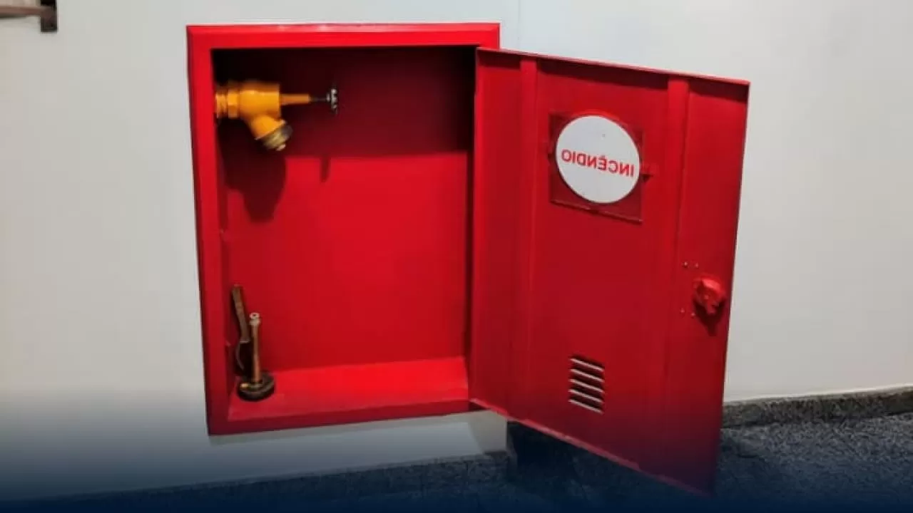 Hidrante de parede vermelho, com porta aberta mostrando equipamento interno, simbolizando a importância de sistemas de incêndio para evitar Penalidades AVCB CLCB.